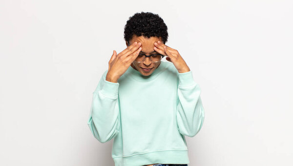 Young afro woman looking stressed and frustrated, working under pressure with a headache and troubled with problems