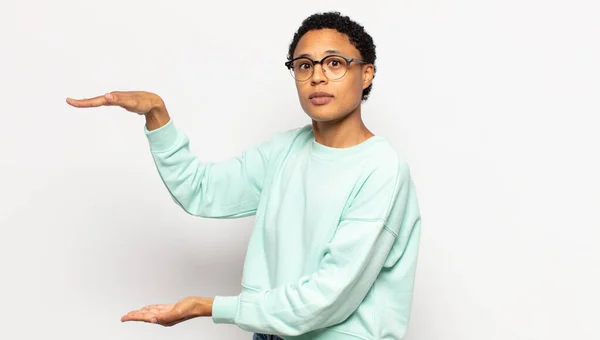 Junge Afro Frau Hält Ein Objekt Mit Beiden Händen Auf — Stockfoto