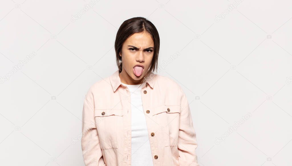 pretty young woman feeling disgusted and irritated, sticking tongue out, disliking something nasty and yucky