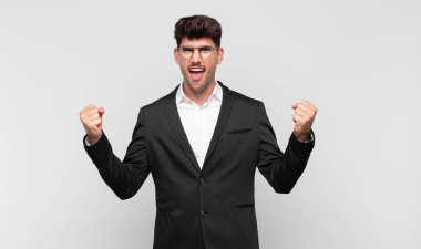 Genç yakışıklı adam mutlu, şaşırmış ve gururlu, bağırıyor ve başarıyı büyük bir gülümsemeyle kutluyor.