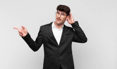 Genç yakışıklı adam gülüyor, mutlu, pozitif ve şaşırmış görünüyor. Yan fotokopi alanını işaret eden harika bir fikrin farkına varıyor.