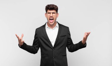 Genç yakışıklı adam öfkeyle bağırıyor, stresli hissediyor ve ellerini havaya kaldırıp neden ben diye bağırıyor.