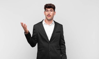 Genç yakışıklı adam kendini mutlu, şaşırmış ve neşeli hissediyor. Pozitif bir tavırla gülümsüyor. Bir çözüm ya da fikir buluyor.