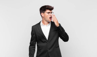 Genç yakışıklı adam tembelce esniyor, uykulu, yorgun ve sıkkın görünüyor.