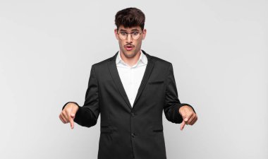 Genç yakışıklı adam şok olmuş, ağzı açık ve şaşkın, inançsızlık ve şaşkınlık içinde bakıyor ve onu işaret ediyor.