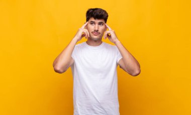 Genç ve yakışıklı bir adam kafası karışmış ya da şüphe içinde, bir fikre odaklanmış, çok düşünüyor, kenarda boşluğu kopyalamaya çalışıyor.