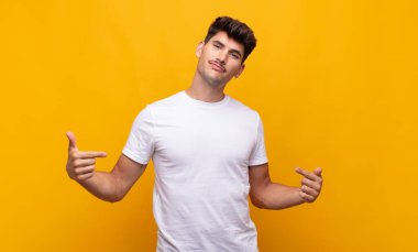 Genç yakışıklı adam gururlu, kibirli, mutlu, şaşırmış ve tatmin olmuş görünüyor, kendini gösteriyor, kazanan gibi hissediyor.