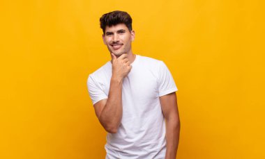 Genç yakışıklı adam gülümsüyor, hayattan zevk alıyor, mutlu, arkadaş canlısı, tatmin olmuş ve tasasız.