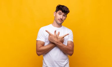 Şaşkın, kafası karışmış, güvensiz ve şüpheyle zıt yönlere bakan genç yakışıklı bir adam.