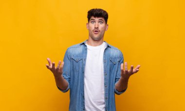 Genç, yakışıklı, ağzı açık ve şaşkın, şok olmuş ve şaşırmış bir adam.