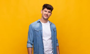 Genç yakışıklı adam mutlu ve arkadaş canlısı görünüyor, gülümsüyor ve sana olumlu bir tavırla göz kırpıyor.