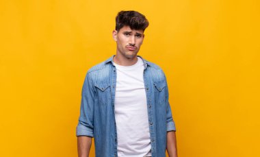 Genç yakışıklı adam üzgün ve mızmız, mutsuz bir bakışla, olumsuz ve hayal kırıklığına uğramış bir tavırla ağlıyor.