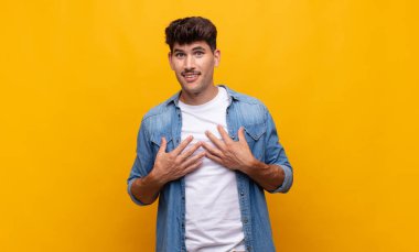 Genç yakışıklı adam mutlu görünüyor, şaşırmış, gururlu ve heyecanlı, kendini gösteriyor.