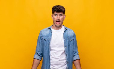 Genç yakışıklı adam korkmuş ve şok olmuş hissediyor, ağzı açık şaşkınlık içinde.