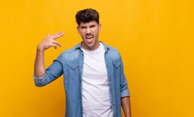 Genç yakışıklı adam mutsuz ve stresli görünüyor, intihar jesti silahla işaret ediyor, kafasını işaret ediyor.