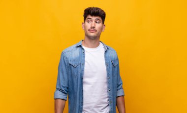 Genç yakışıklı adam merak ediyor, mutlu düşünceler ve fikirler düşünüyor, hayal kuruyor, kenarda yer arıyor.