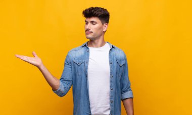 Genç yakışıklı adam kendini mutlu hissediyor ve gülümsüyor. Yanında duran bir nesneye ya da konsepte bakıyor.