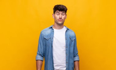 Genç ve yakışıklı adam şapşal ve komik görünüyor. Şaşı bakışlı, şakacı ve şakacı.