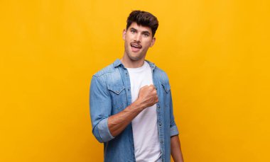 Genç yakışıklı adam mutlu, pozitif ve başarılı hissediyor, bir meydan okumayla karşılaştığında motive oluyor veya iyi sonuçları kutluyor.