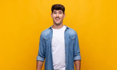 Genç yakışıklı adam mutlu ve hoş bir şekilde şaşırmış görünüyor. Büyülenmiş ve şok olmuş bir ifadeyle heyecanlanıyor.