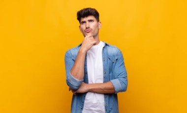 Genç yakışıklı adam düşünüyor, kuşkulu ve şaşkın hissediyor, farklı seçeneklerle, hangi kararı vereceğini merak ediyor.