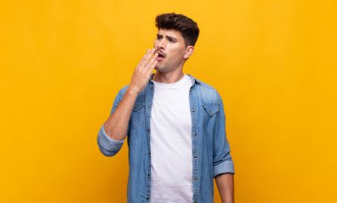 Genç yakışıklı adam tembelce esniyor, uykulu, yorgun ve sıkkın görünüyor.