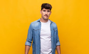 Genç yakışıklı adam kendini cahil, kafası karışmış ve hangi seçeneği seçeceği konusunda kararsız hissediyor, sorunu çözmeye çalışıyor.