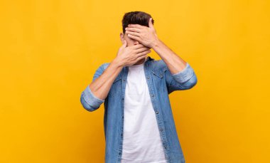 Genç yakışıklı adam kameraya hayır diyen iki eliyle yüzünü kapatıyor! Resimler reddediliyor ya da yasaklanıyor