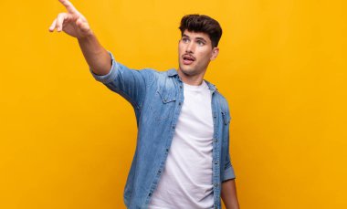 Genç yakışıklı adam şaşkın ve şaşırmış hissediyor, hayranlıkla yukarı bakıyor, şaşırmış, ağzı açık bakıyor.