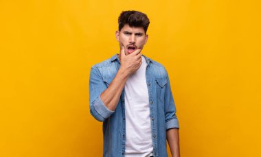 Ağzı ve gözleri açık, eli çenesinde genç ve yakışıklı bir adam. Hoş olmayan bir şok geçiriyor.