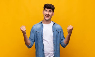 Genç yakışıklı adam mutlu, pozitif ve başarılı hissediyor, zaferi, başarıları ya da iyi şansı kutluyor.