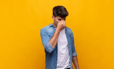 Genç yakışıklı, stresli, mutsuz ve hayal kırıklığına uğramış, alınlı ve şiddetli baş ağrısı çeken bir adam.