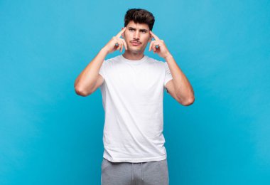 Genç ve yakışıklı bir adam kafası karışmış ya da şüphe içinde, bir fikre odaklanmış, çok düşünüyor, kenarda boşluğu kopyalamaya çalışıyor.