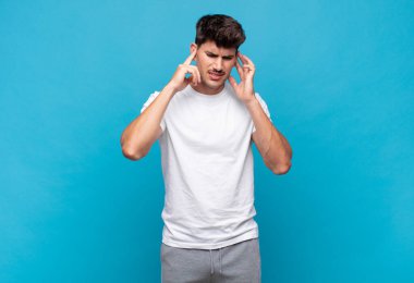 Genç yakışıklı adam sinirli, stresli ve sinirli görünüyor, iki kulağını da sağır edici bir ses, ses ya da yüksek sesle kapatıyor.