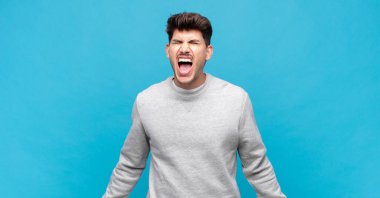 Genç yakışıklı adam agresif bir şekilde bağırıyor, çok kızgın, hayal kırıklığına uğramış, öfkeli ya da sinirli görünüyor, hayır