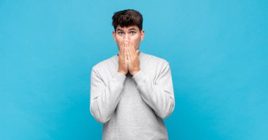 Genç yakışıklı adam endişeli, üzgün ve korkmuş, elleri ağızda, endişeli ve berbat görünüyor.