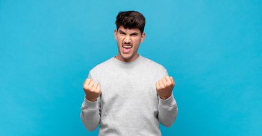 Genç yakışıklı adam zaferle bağırıyor, gülüyor, mutlu ve heyecanlı hissediyor başarıyı kutlarken.