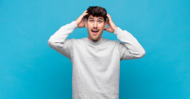 Genç yakışıklı adam el ele tutuşuyor, ağzı açık, son derece şanslı, şaşırmış, heyecanlı ve mutlu hissediyor.