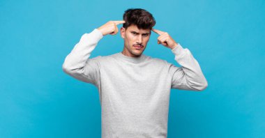 Ciddi ve konsantre görünümlü, beyin fırtınası yapan ve zorlu bir sorunu düşünen genç yakışıklı bir adam.