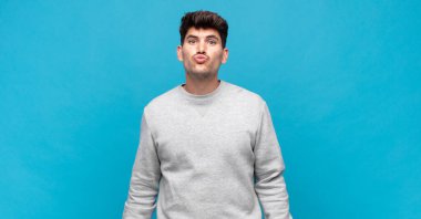 Genç yakışıklı adam dudaklarını birbirine bastırıyor, tatlı, eğlenceli, mutlu, sevimli bir yüz ifadesiyle, öpücük yolluyor.