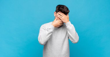 Genç yakışıklı adam kameraya hayır diyen iki eliyle yüzünü kapatıyor! Resimler reddediliyor ya da yasaklanıyor