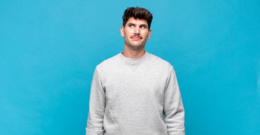 Genç yakışıklı adam şok olmuş, mutlu, şaşkın ve şaşırmış hissediyor, ağzı açık bir şekilde yana bakıyor.