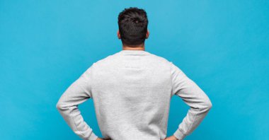 Genç, yakışıklı bir adam kafası karışık ya da dolu ya da şüphe ve soru dolu, merak ediyor, elleri kalçasında, dikiz aynasından.