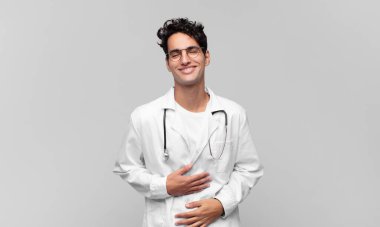 Genç doktor komik bir şakaya yüksek sesle gülüyor, mutlu ve neşeli hissediyor, eğleniyor.