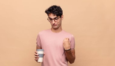 Kahvesi olan genç yakışıklı bir adam kibirli, başarılı, pozitif ve gururlu görünüyor.