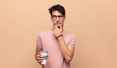 Kafası karışık ve şüpheci, farklı seçenekleri olan, hangi kararı vereceğini merak eden genç ve yakışıklı bir adam.