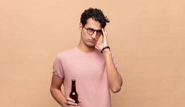 Birası olan genç bir adam yorgun, sıkıcı ve sıkıcı bir işten sonra sıkılmış, hayal kırıklığına uğramış ve uykulu hisseder.