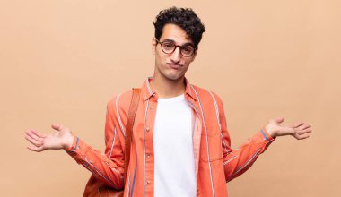 Genç öğrenci şaşkın ve şaşkın hissediyor, şüpheci, farklı seçenekleri tartıyor veya komik bir ifadeyle seçiyor.