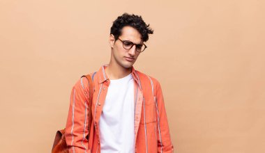 Genç bir öğrenci üzgün, üzgün ya da kızgın. Olumsuz bir tavır sergiliyor, anlaşmazlık içinde kaşlarını çatıyor.