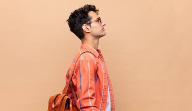 Profil görünümündeki genç öğrenci ilerideki boşluğu kopyalamaya çalışıyor, düşünüyor, hayal ediyor ya da hayal kuruyor